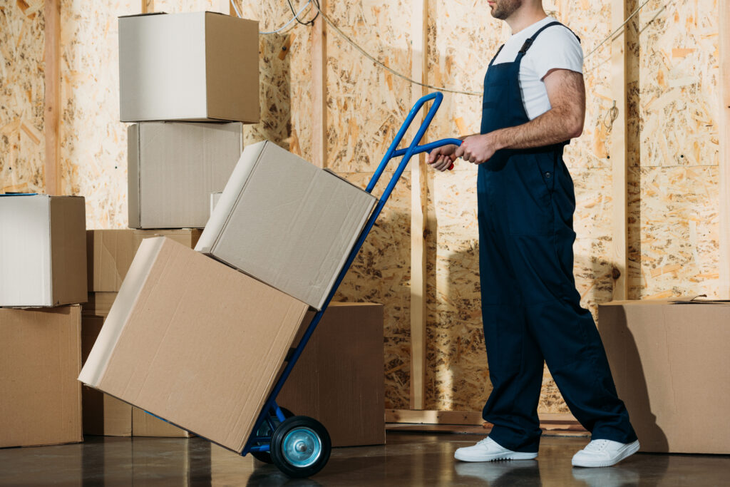 Delivery man carrying boxes on hand truck
