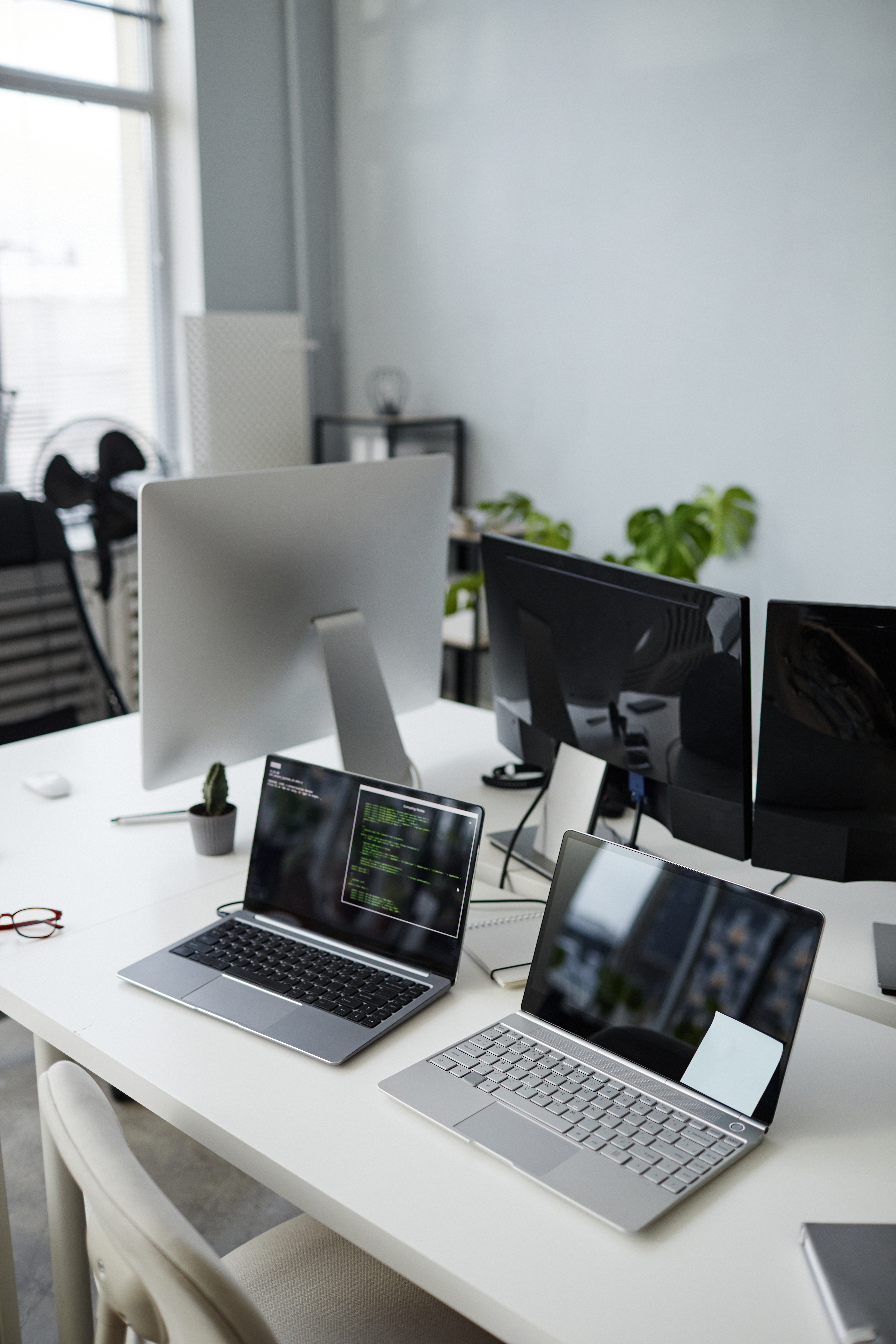 Part of office with group of laptops and computer monitors on desks